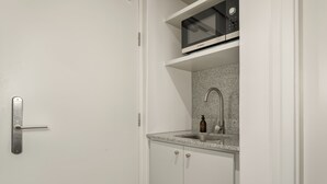 Une cuisine compacte équipée d’un four à micro-ondes, d’un évier et de placards.