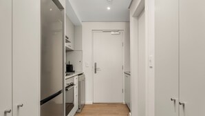 Un couloir étroit avec des armoires blanches et une porte au fond.