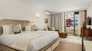 Une chambre d’hôtel moderne dotée d’un grand lit, d’un téléviseur à écran plat, d’une petite table et donnant sur le balcon extérieur.