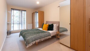 A bedroom with a bed, a bedside table, a mirror, and a wardrobe. - Bright 2BR Flat • Parking • 1 Min to Tube/Metro • Next to London Museum - Pass the Keys (London)