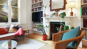 Un salon chaleureux avec une cheminée, des étagères à livres, un téléviseur et un coin salon confortable.