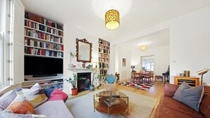 Un salon spacieux avec une grande bibliothèque, une cheminée, un téléviseur et un coin salon confortable.