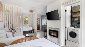 Ein modernes Schlafzimmer mit einem Bett, einem Fernseher über einem Kamin und einer Waschmaschine in der Ecke.
