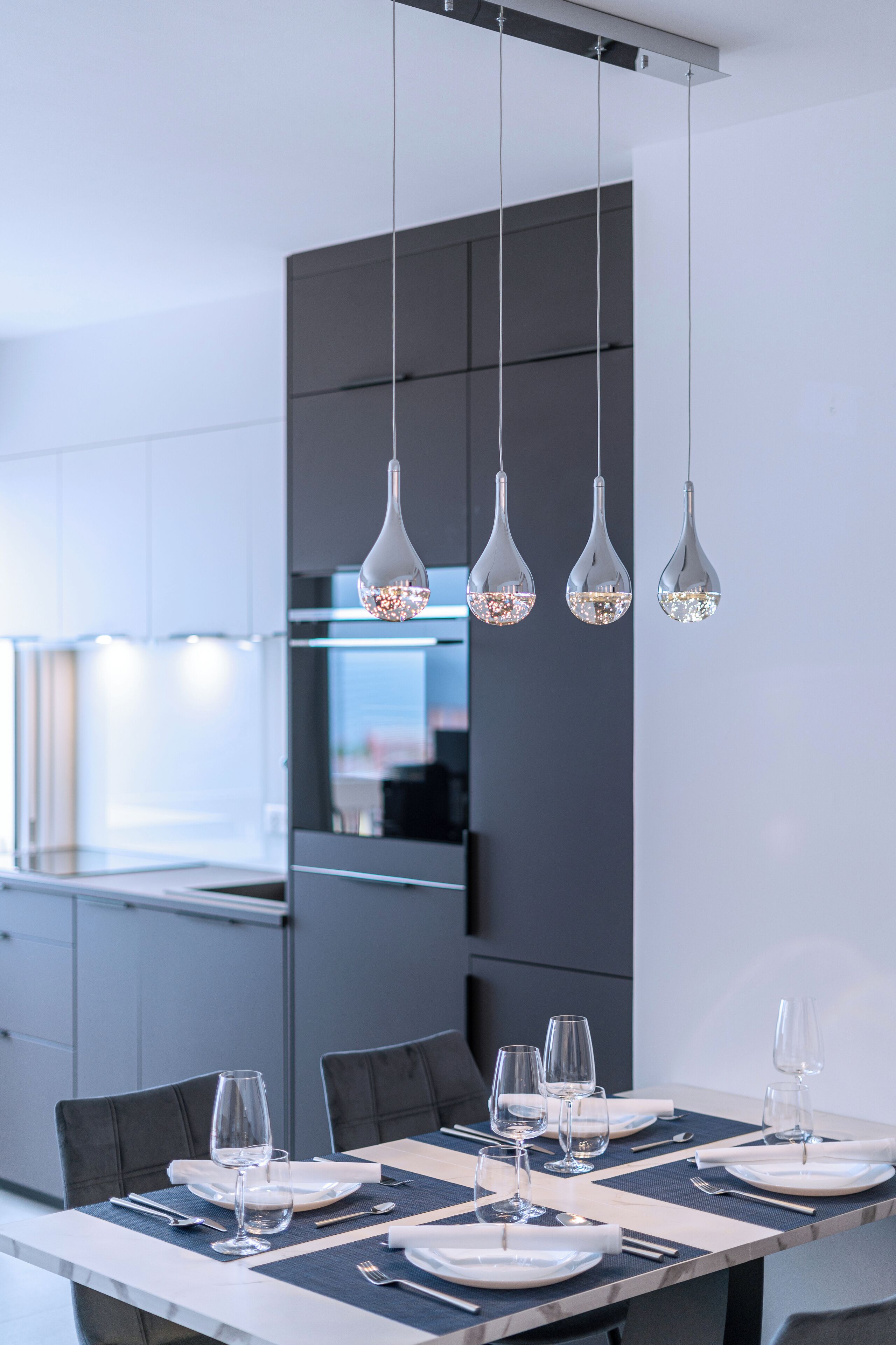 Ein moderner Essbereich mit einem langen Tisch, gedeckt für sechs Personen, im minimalistischen Stil mit dunklen Stühlen und einer hellen Tischdecke.