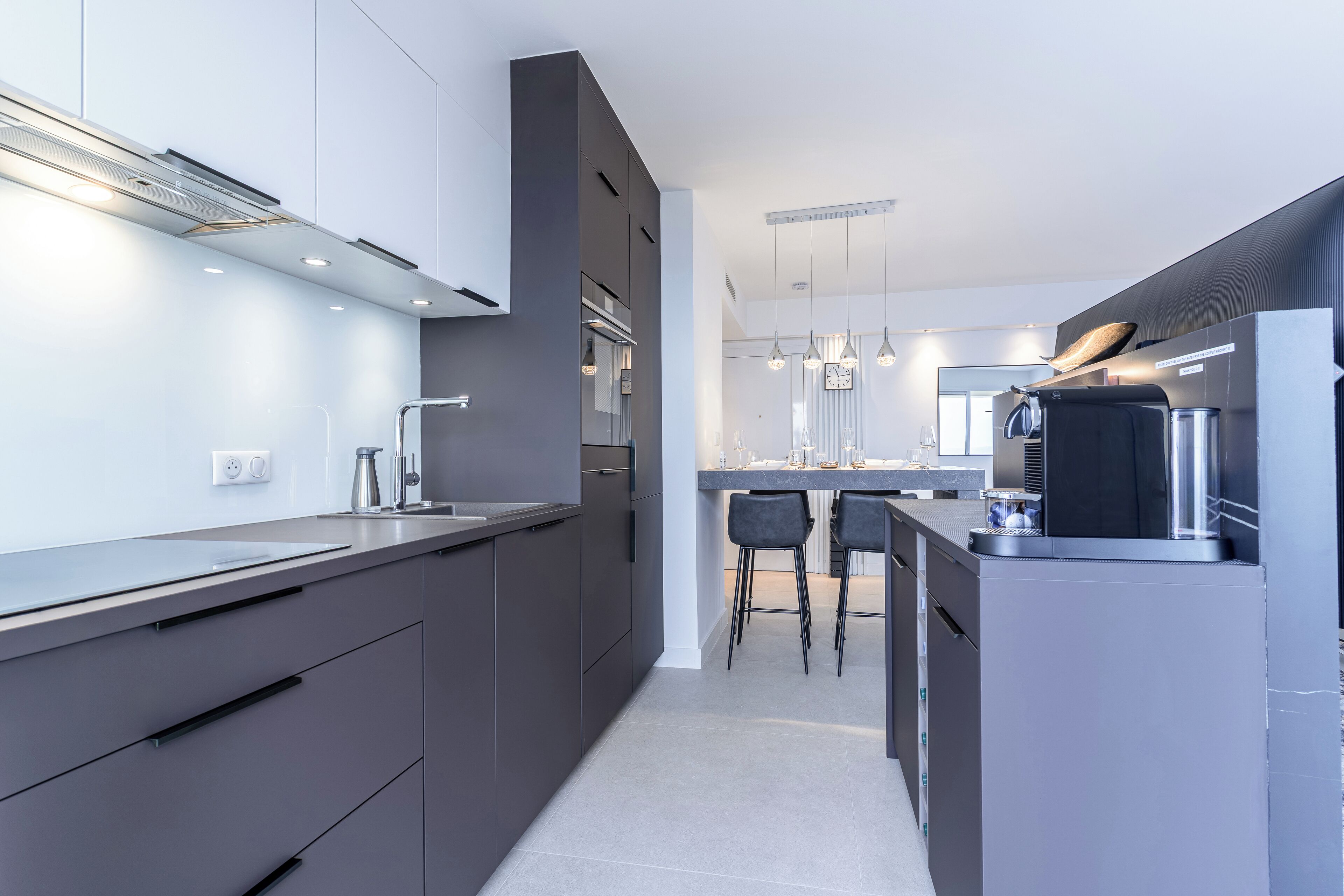 Cozinha moderna com armários escuros, eletrodomésticos de aço inoxidável e uma ilha central com banquetas.