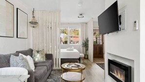 Ein modernes Wohnzimmer mit einer Couch, einem Couchtisch, einem Kamin und einem an der Wand befestigten Fernseher.