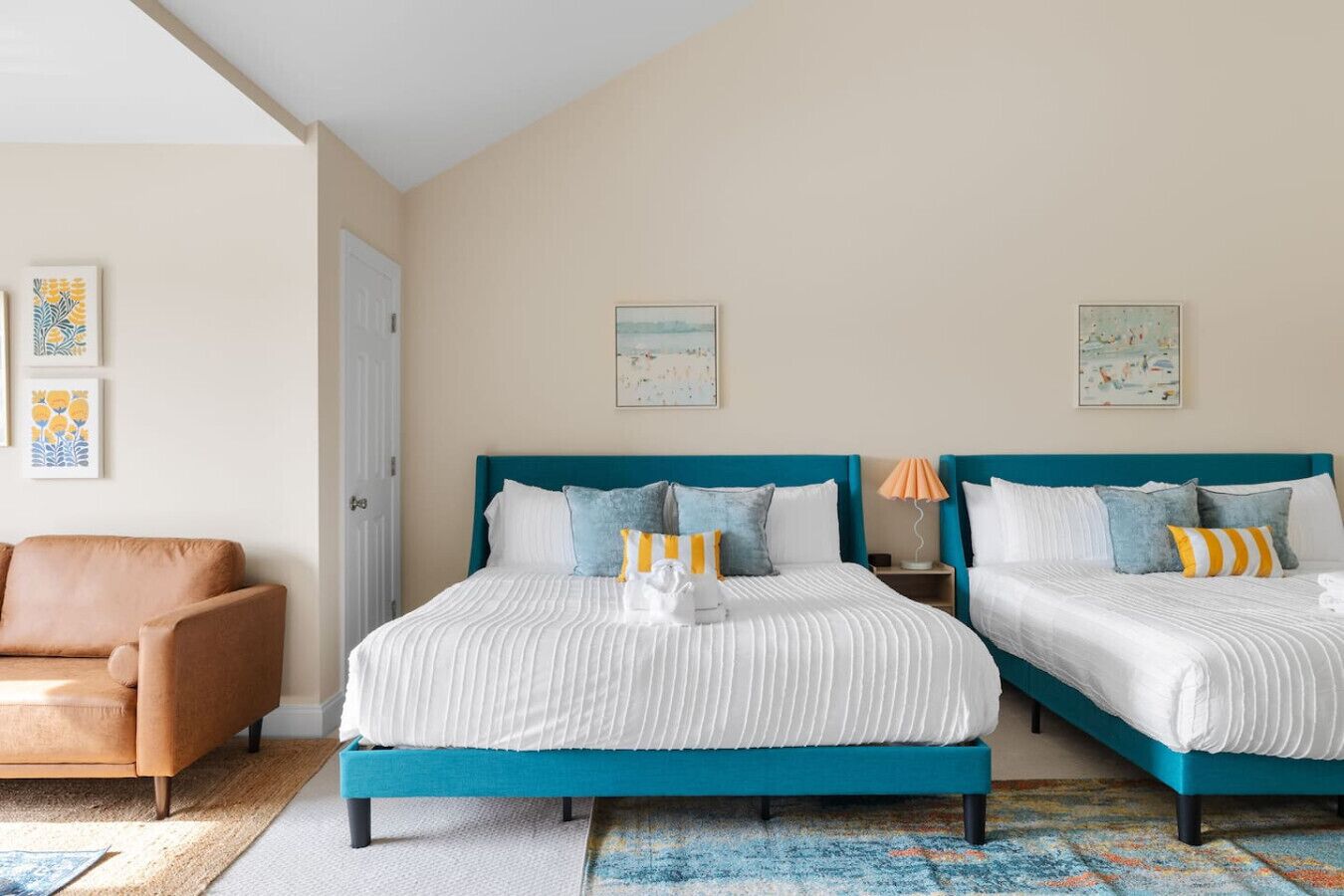 Habitación de hotel con dos camas, un sofá y obras de arte en las paredes.