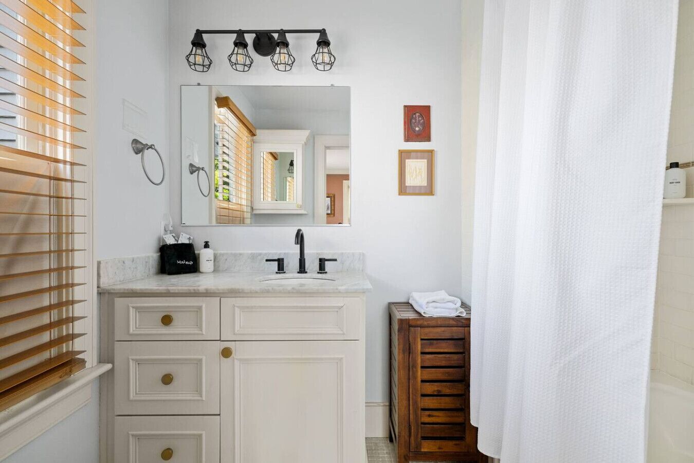 A bathroom with a white vanity, a mirror, and a shower curtain.