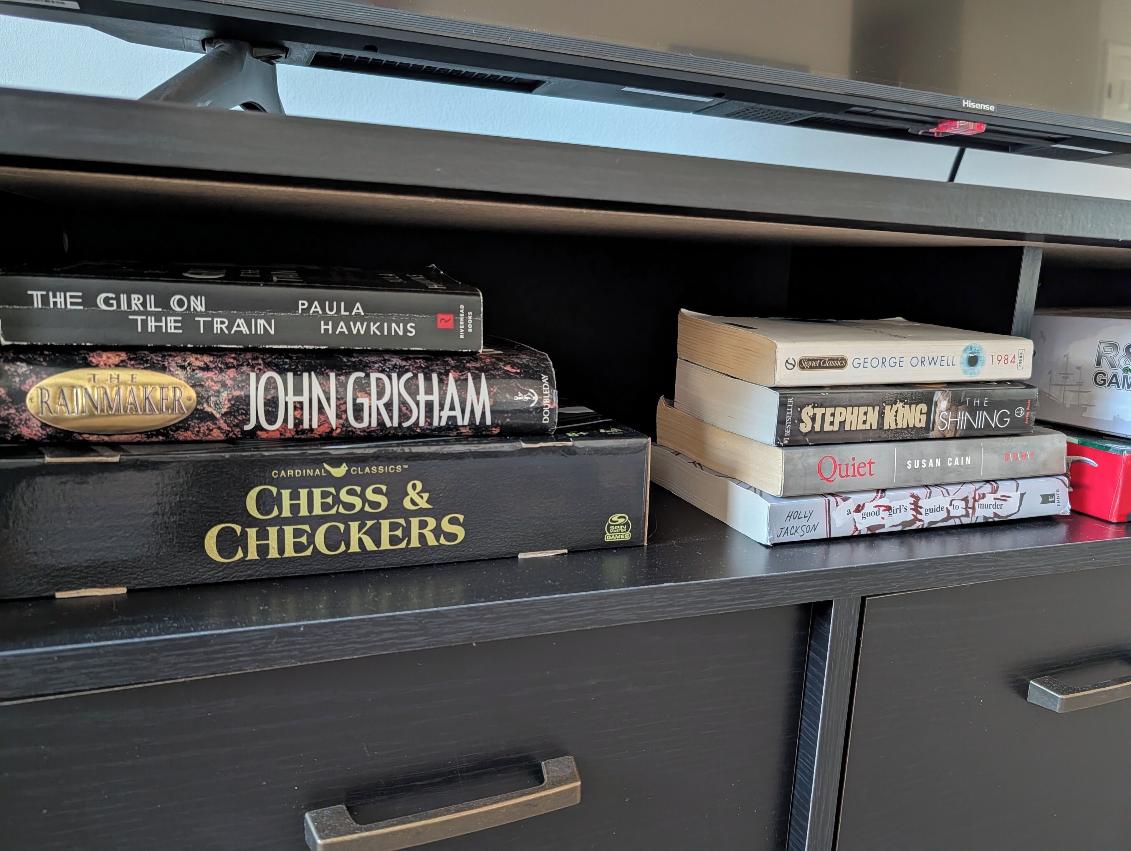 Uma estante com diversos livros, incluindo títulos como 'The Girl on the Train' e 'Chess & Checkers'.