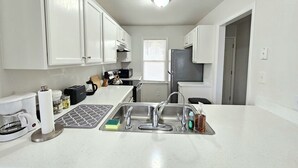 A compact kitchen with white cabinets, a stainless steel sink, and a coffee maker.