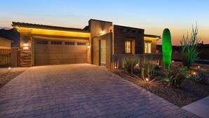 Een modern huis met garage, een goed verlichte oprit en een cactusgaard.