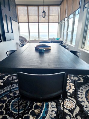 A conference room with a long table, chairs, and a view of the sea through large windows. - Sun Mountain Crest Villa is up the mountain with ocean view & centrally located. (St Thomas)