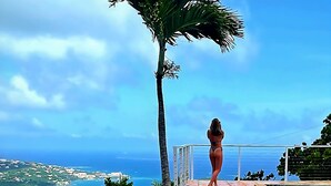 Una donna in piedi su un patio piastrellato con vista sulla piscina e sull'oceano.