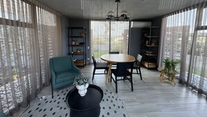 A modern living room with a round wooden table, black chairs, a green sofa, and a coffee table with a vase. - Dpto. cerca de Ternium y UANL (Monterrey)