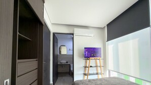 A bedroom with a bed, a wardrobe, a bathroom with a mirror, and a TV on a stand. - Dpto. cerca de Ternium y UANL (Monterrey)