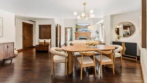 A spacious dining area with a wooden table and chairs, a fireplace, and a television. - Beaver Creek Penthouse | Pool, Hot Tub, Walkable (Avon)