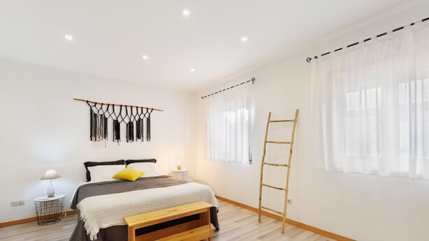 A bedroom with a bed, bedside table, lamp, wall art, and a wooden ladder. - Tour House – Rio Tinto: Cozy Retreat for a Relaxing Stay (Rio Tinto)