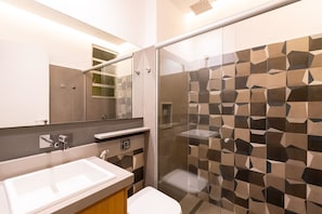 A modern bathroom with a glass shower enclosure, a white sink, and a large mirror. - Studio Beach View in Copacabana A 3196/502 (Rio de Janeiro)