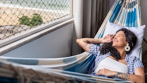 A person lying in a hammock by a window with a view of a beach. - 2bdrs With Copacabana Beach View A 2936/1202 (Rio de Janeiro)