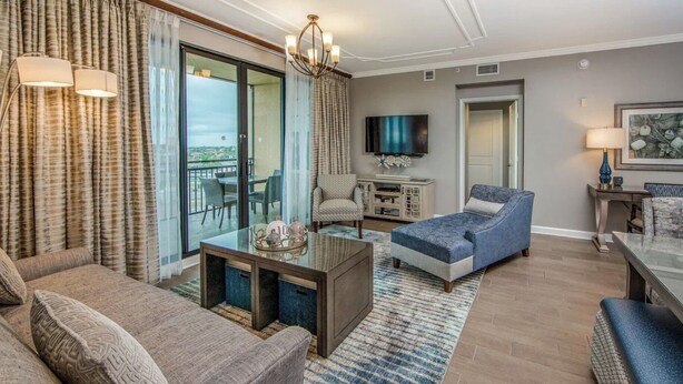 A modern living room with a sofa, a blue armchair, a coffee table, and a TV. - Rare Luxurious 3 Bedroom, 3 Bathroom Condo on Marco Island, FL (Marco Island)
