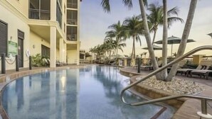 A swimming pool with a clear blue water surface, surrounded by palm trees and lounge chairs. - Rare Luxurious 3 Bedroom, 3 Bathroom Condo on Marco Island, FL (Marco Island)