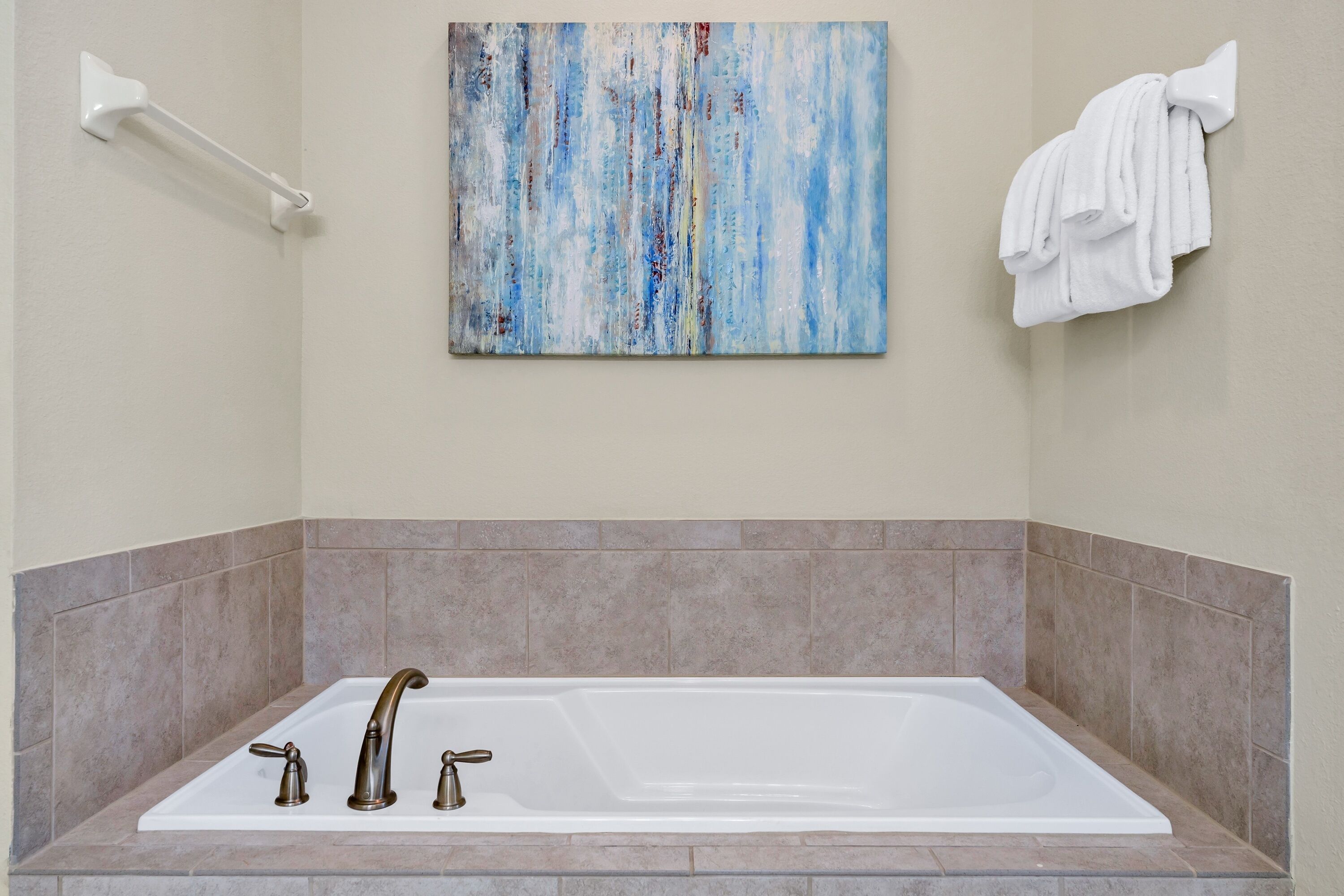 A bathroom with a bathtub, a towel rack, and a wall-mounted towel.