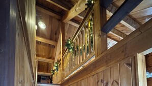 Eine Holztreppe mit Geländer, verziert mit Lichtern, die zu einer oberen Etage führt.