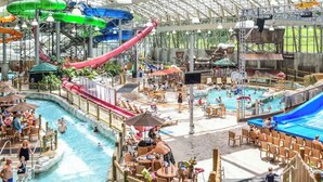 A water park with multiple slides and pools, surrounded by wooden deck chairs and umbrellas.
