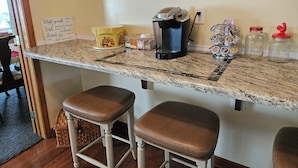 Un comptoir de cuisine avec une machine à café, des bocaux et un panneau décoratif.