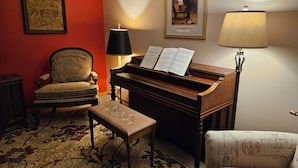 Une pièce comprenant un piano à queue, une chaise, un banc et une lampe.
