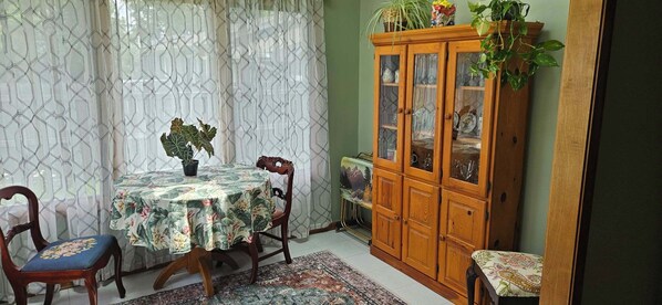 A dining area with a round table, chairs, a cabinet with glass doors, and a potted plant.