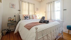 A bedroom with a bed, bedside table, and a window. - Charming Modern Farmhouse Retreat (Terre Haute)