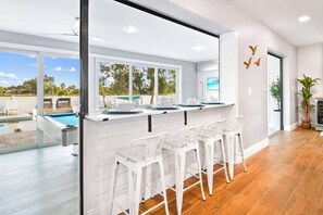 Una cocina moderna con barra, ventanas amplias y vista a la piscina.