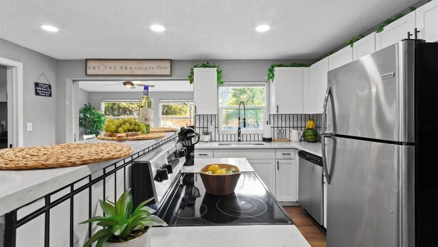 Une cuisine moderne avec des meubles blancs, un réfrigérateur en acier inoxydable et une cuisinière noire.