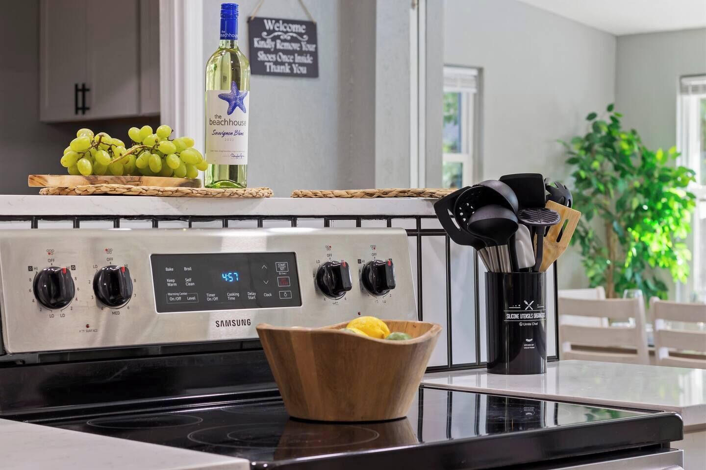 Een keuken met een Samsung fornuis, een fles wijn en een schaal met citroenen op het aanrecht.