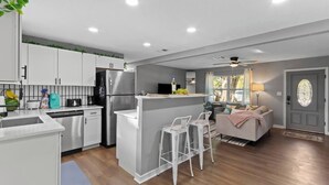 Une cuisine moderne avec des meubles blancs, un réfrigérateur en acier inoxydable et un coin bar.