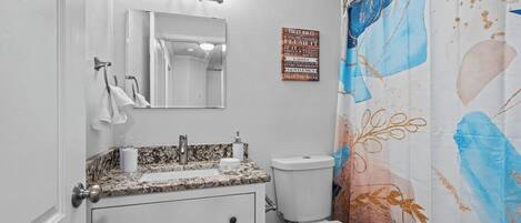 A bathroom with a white vanity, a toilet, and a shower curtain with a floral pattern.