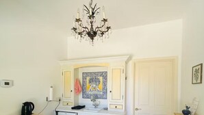 A compact kitchen with a microwave, kettle, and a small refrigerator. A chandelier hangs from the ceiling, and a patterned rug is on the floor. - Italian Style 2 Bedroom Guesthouse and Gardens In Beautiful Topanga (Topanga)