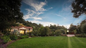 A well-maintained lawn, a house with a red-tiled roof, and a variety of trees and shrubs. - Italian Style 2 Bedroom Guesthouse and Gardens In Beautiful Topanga (Topanga)