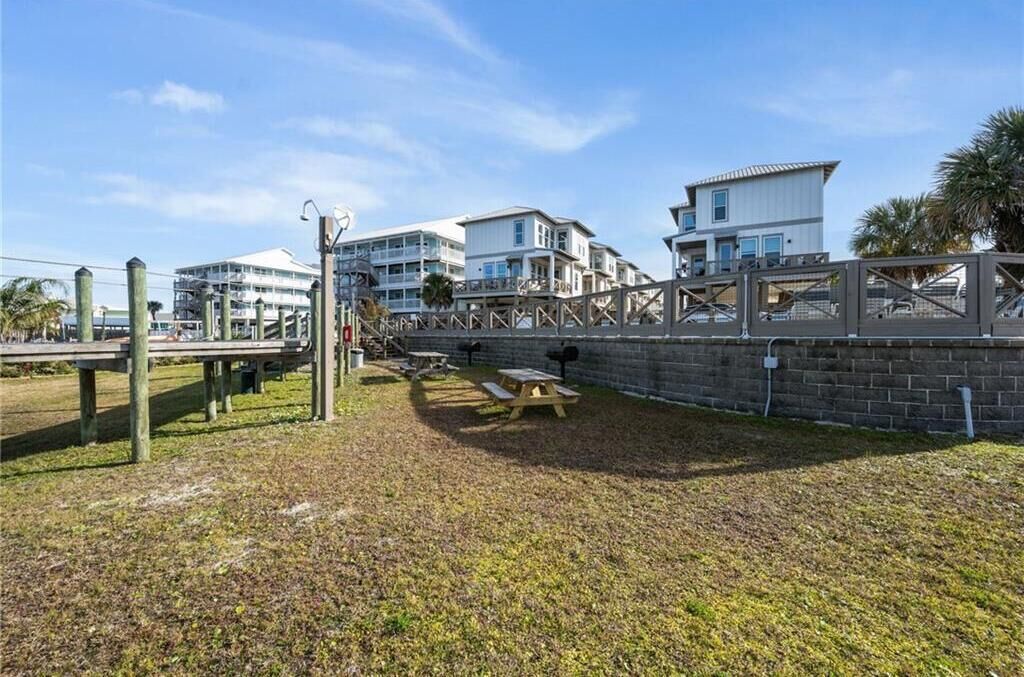 Une zone côtière dotée d’une promenade en bois, de tables de pique-nique et d’un mur en briques.