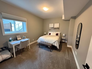 Une chambre à coucher avec un lit, des tables de chevet, un bureau et une fenêtre.