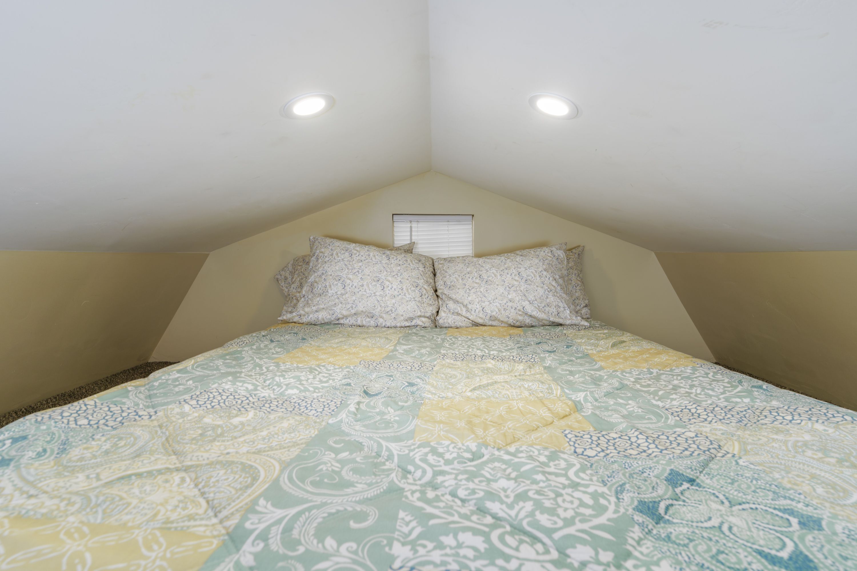 A bedroom with a bed, two pillows, a window, and a ceiling light.