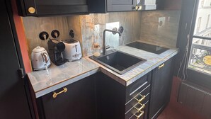 Una cucina compatta con mobili scuri, un lavello incassato, un tostapane, un bollitore e una macchina da caffè.