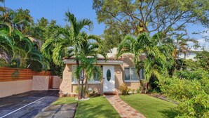 A house with a paved driveway, a well-maintained lawn, and a variety of tropical plants. - Private Tropical Garden Home - Walk to Las Olas (Fort Lauderdale)