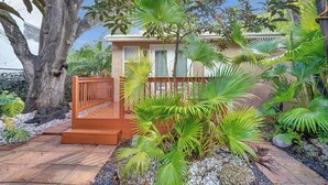 A house with a wooden deck, surrounded by tropical plants and a large tree. - Private Tropical Garden Home - Walk to Las Olas (Fort Lauderdale)