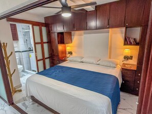 A bedroom with a bed, bedside lamps, a nightstand, a wooden headboard, and a ceiling fan. - Boana Torre Malibu #105 , Ocean view, romantic zone (Puerto Vallarta)
