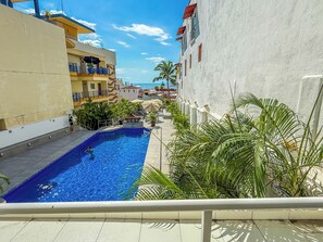 A swimming pool with a view of a cityscape, surrounded by buildings and palm trees. - Boana Torre Malibu #105 , Ocean view, romantic zone (Puerto Vallarta)