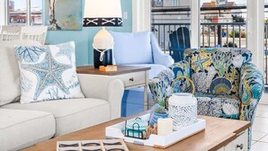 A room with a white sofa, a patterned armchair, a wooden coffee table, and a ceiling fan. - The Bayside Oasis at Ocean Bliss | Boardwalk (Ocean City)
