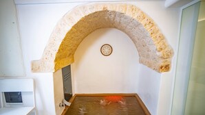 A room with a stone archway, a small circular emblem, and a water feature. - Nivèra White Allure Maison · Suite Flùa – Ostuni (Ostuni)