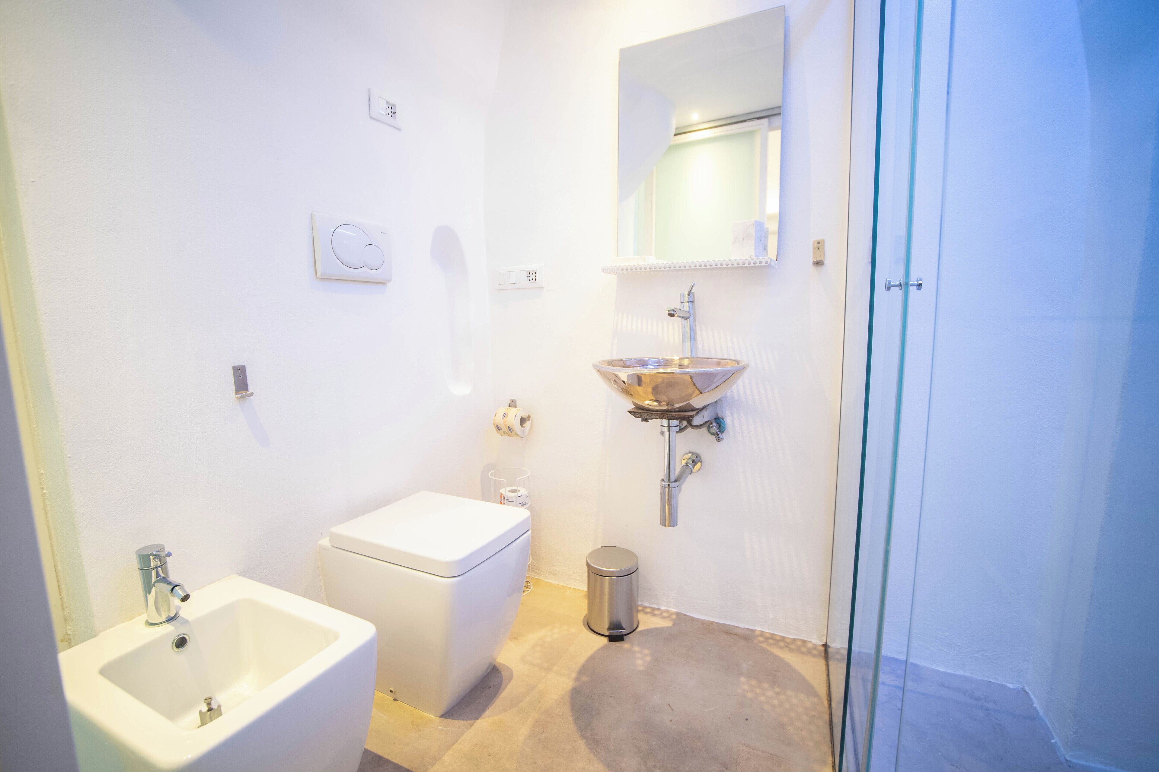 Ein modernes Badezimmer mit weißem Waschbecken, WC und Duschkabine aus Glas.